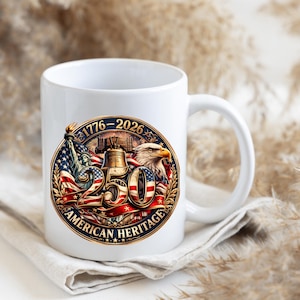 K&ouml;nnte beinhalten: Wei&szlig;e Keramik-Tasse mit patriotischem Design. Das Design enth&auml;lt den Text "1776-2026" und "250 AMERICAN HERITAGE" mit Bildern der Freiheitsstatue, eines Adlers und der Liberty Bell, vor dem Hintergrund der amerikanischen Flagge.