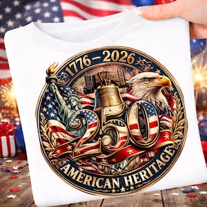 K&ouml;nnte beinhalten: Wei&szlig;es T-Shirt mit einem patriotischen Design. Das Design zeigt die Freiheitsstatue, die Liberty Bell, einen Adler und den Text "250 AMERICAN HERITAGE 1776-2026" in einem kreisf&ouml;rmigen Emblem in Rot, Wei&szlig; und Blau.