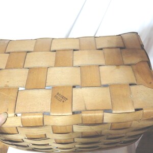 May include: A woven basket made of natural materials with a light brown color. The basket has a rectangular shape and is made with a woven pattern. The text "Basket Ville" is printed on the bottom of the basket.