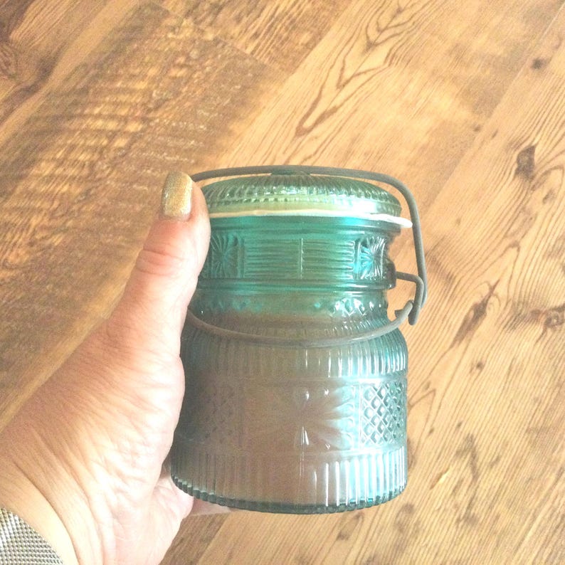 May include: A teal blue glass jar with a wire bail handle. The jar has a textured, diamond-shaped pattern.