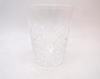 May include: A clear glass tumbler featuring a faceted diamond-cut pattern around the lower exterior. The vessel has a smooth, unadorned rim and a thick, heavy base with a starburst design etched into the bottom, reflecting light through the glass.