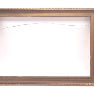 May include: A rectangular picture frame with a metallic gold finish and a scalloped edge pattern along the outer border. The frame is empty and features a thin, dark metal hanging wire stretched across the back opening for wall mounting.