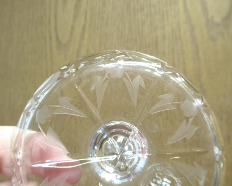 Op de afbeelding: Transparante glazen kom met ge&euml;tste bloemen- en bladerenpatronen. De kom heeft een gedetailleerd patroon rond de rand en een centraal ontwerp. Het transparante glas laat licht door, waardoor de ge&euml;tste details worden benadrukt.