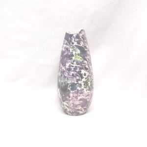 May include: A tall, decorative vase with a marbled pattern in shades of purple, green, and white. The vase has a unique, slightly asymmetrical shape and a textured surface. The vase is a decorative item.