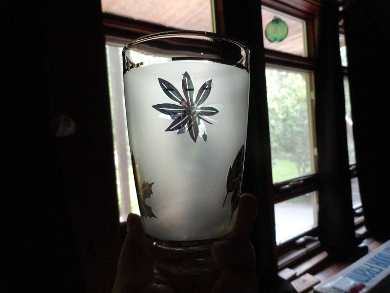 May include: A frosted glass with a silver floral design. The glass is partially filled with a white liquid.