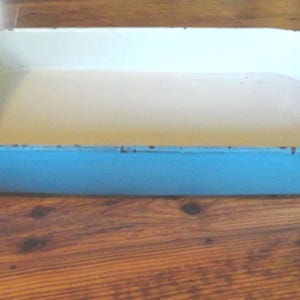 May include: A light blue rectangular baking dish with a white interior. The dish has a slightly worn appearance.