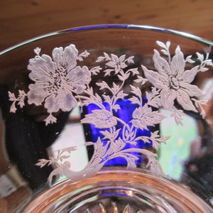 May include: A clear glass bowl with an etched floral design. The design features delicate flowers and leaves in a white color.
