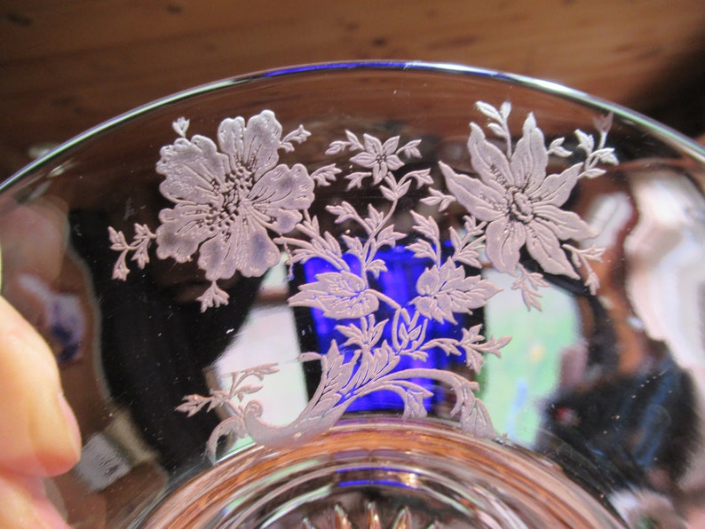 May include: A clear glass bowl with an etched floral design. The design features delicate flowers and leaves in a white color.