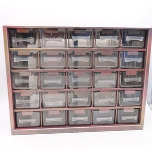 May include: A wooden storage cabinet with a pinkish-brown frame and multiple clear plastic drawers. The drawers are arranged in rows and columns, providing organized storage for small items. The cabinet is designed for efficient organization.