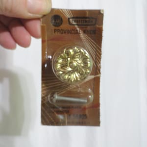 May include: A gold-colored Craftsman Provincial Knob with a floral design, packaged with a screw. The package is brown with white text.