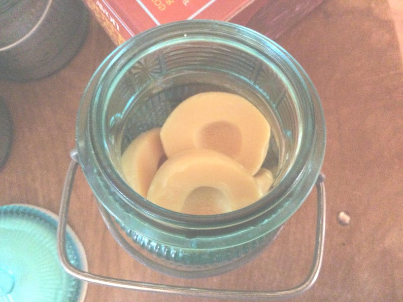 May include: A glass jar with a metal lid and handle, filled with sliced, light brown fruit. The jar is on a wooden surface.