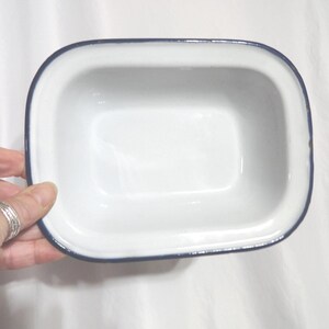 May include: White enamel baking dish with a blue rim. The dish is rectangular and has a smooth, glossy finish.