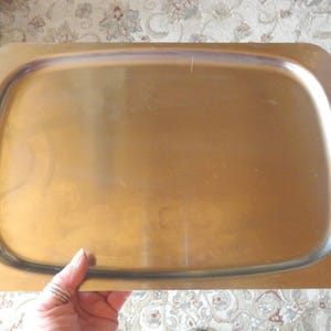 May include: A silver serving tray with an ornate design around the edge. The tray is made of metal and has a smooth, reflective surface.