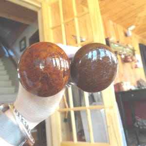 May include: Two round, brown, wooden door knobs with a marbled pattern.