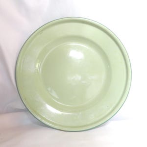 May include: A pale green enamel dinner plate with a light green rim.