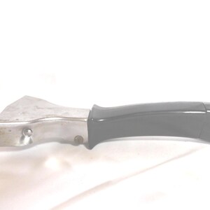 May include: A metal and black handle pot lifter. The lifter has a silver metal head and a black plastic handle. The handle is curved for a comfortable grip. The lifter is designed to lift hot pots and pans.
