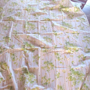 May include: White fabric with a yellow and green floral pattern. The fabric has a striped pattern with vertical lines.