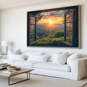 Puede incluir: Gran obra de arte enmarcada que representa una ventana abierta con vistas a una vibrante puesta de sol sobre una cordillera. El marco de la ventana es de color marrón oscuro y el paisaje presenta un exuberante follaje verde. El cielo está lleno de tonos cálidos anaranjados y amarillos.