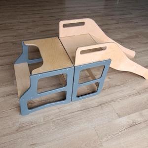 Op de afbeelding: Een houten speelset met een lichtblauw frame en natuurlijke houten oppervlakken. De set bevat een opstapje en een glijbaan, ontworpen voor jonge kinderen. Het opstapje heeft een rechthoekige vorm met uitgesneden handgrepen.
