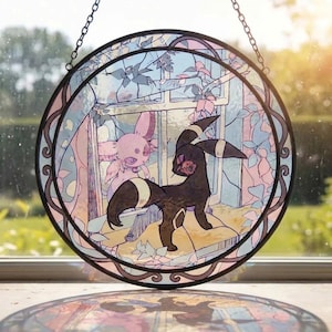 May include: A circular stained glass suncatcher featuring a black creature with yellow rings and a pink creature with large ears. The design includes a window frame and foliage in shades of pink, blue, and white, all enclosed in a dark metal frame.
