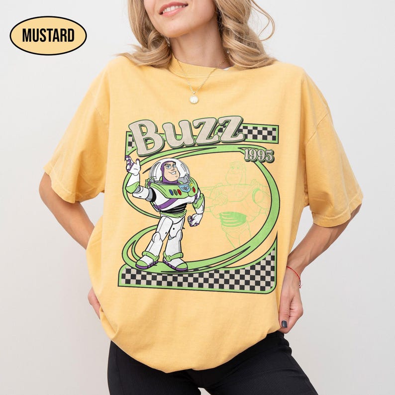 Peut inclure: T-shirt moutarde avec un motif de Buzz l'&Eacute;clair de Toy Story. Le design comprend le mot "Buzz", l'ann&eacute;e "1995" et un contour vert de Buzz. Le t-shirt a une coupe d&eacute;contract&eacute;e.
