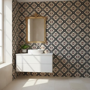 Peut inclure: Une salle de bain avec un meuble-lavabo blanc, un lavabo rond et un miroir doré. Les murs sont ornés de carreaux à motifs avec des motifs floraux noirs, beiges et bordeaux. Une petite plante en pot est présente.