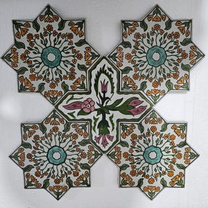 Peut inclure: Composition de carreaux décoratifs en céramique. Chaque carreau en forme d'étoile présente un motif floral avec un cercle central turquoise, des fleurs orange et des feuilles vertes. Le carreau central a des éléments floraux roses et verts.