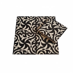 May include: A set of square tiles with a black and white swirling pattern. The tiles are arranged in a group, with one tile slightly raised, showcasing the design. The pattern is a repeating, stylized floral motif.