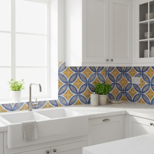 Könnte beinhalten: Eine helle Küche mit weißen Schränken, einem Doppelwaschbecken und einem Fenster. Der Fliesenspiegel zeigt ein sich wiederholendes Muster aus blauen und gelben Kreisdesigns. Kleine Topfpflanzen sorgen für einen Hauch von Grün.