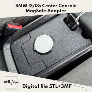 Może przedstawiać: Czarny adapter MagSafe do konsoli środkowej dla BMW i3/i3s. Adapter posiada okrągły obszar ładowania MagSafe i jest przeznaczony do wpasowania w konsolę samochodu. Na zdjęciu widoczny jest również tekst "Digital file STL+3MF".