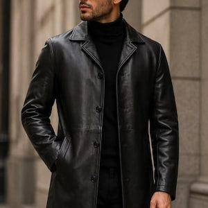 May include: A black leather trench coat featuring a classic collar, long sleeves, and a button-front closure. The coat is worn over a black turtleneck sweater. The leather has a smooth finish and the design includes side pockets and a straight hem.