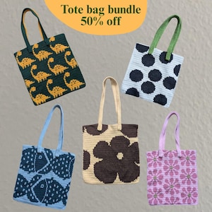 Puede incluir: Colección de cinco bolsas tote hechas a mano con varios diseños. Los diseños incluyen dinosaurios, lunares, peces, una flor grande y patrones florales. Cada bolsa tiene un color de asa a juego. El texto "Tote bag bundle 50% off" es visible.