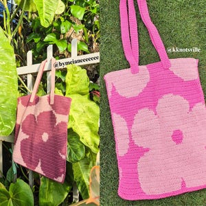 Puede incluir: Bolso tote de crochet hecho a mano con un dise&ntilde;o floral en tonos rosa y rosa claro. El bolso presenta grandes flores y asas rosas. El texto "@kknottsville" es visible. El bolso se muestra al aire libre, sobre un fondo verde.