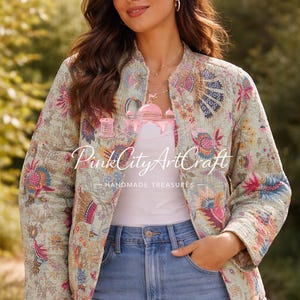 Puede incluir: Chaqueta acolchada verde claro con estampados florales y cachemir en rosa, azul y amarillo. La chaqueta tiene cuello mandarín y se lleva sobre una camiseta blanca y vaqueros azules. El texto "Pink City ArtCraft - HANDMADE TREASURES" es visible.