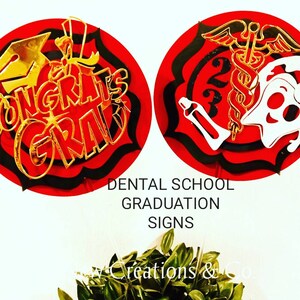May include: Two red and black circular signs with gold accents. The first sign says "Congrats Grad" with a graduation cap. The second sign has a caduceus and a tooth with a toothbrush. The text below the signs reads "Dental School Graduation Signs".