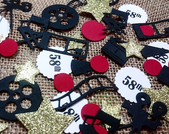 May include: Black and gold confetti with a movie theme. The confetti includes film reels, stars, clapperboards, and circles with the text "58th" on them.