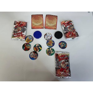 May include: A collection of vintage trading card packs, cards, and game pieces. The packs are silver with red and white graphics. The game pieces are circular with colorful character illustrations. Two cards with text are also present.