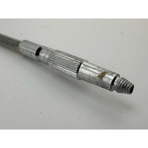 May include: Close-up of a metallic, industrial component. The piece has a cylindrical shape with a threaded end and a ridged section. A braided cable extends from the component, suggesting a mechanical or electrical application.