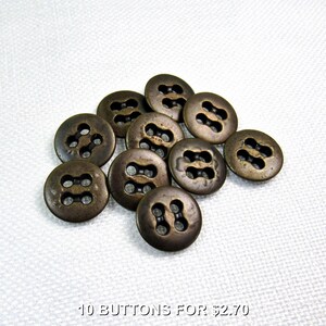 May include: Ten antique bronze-coloured buttons are displayed. Each button is round with a distinctive four-hole design. The buttons have a slightly aged appearance, suggesting vintage or retro styling. Suitable for sewing, crafts, or adding a touch of classic charm to garments.