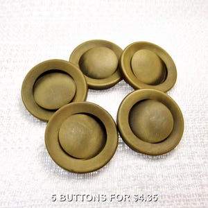 May include: Five round, brass-colored buttons with a smooth, domed center and a wide, flat outer rim. The buttons have a matte finish and are arranged in a circular pattern. The text 5 BUTTONS FOR $4.35 is printed at the bottom of the image.