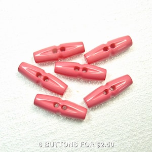 Puede incluir: Seis botones de palanca rosas con dos agujeros cada uno, dispuestos sobre una superficie blanca. Los botones son de un color sólido y brillante. El texto en la parte inferior dice "6 BUTTONS FOR $2.50".