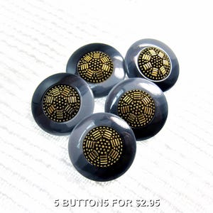 May include: A set of five round buttons, each featuring a smooth, dark gray outer rim and a textured, metallic gold-toned center with a geometric pattern of raised dots and bars. The buttons are arranged in a cluster on a white surface.