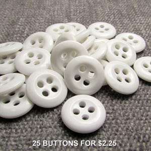 May include: A pile of 25 white plastic buttons with four holes each.  25 BUTTONS FOR $2.25