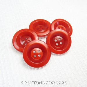 May include: Five bright red buttons with a slightly concave design. Each button has either three or four holes for sewing. The buttons are arranged on a white surface. The text "5 BUTTONS FOR $2.85" is at the bottom.