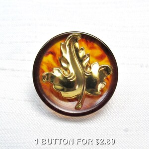 May include: A round button with a gold-colored leaf design. The button has a brown outer ring and a center with orange and yellow marbling. The text "1 BUTTON FOR" is visible at the bottom.