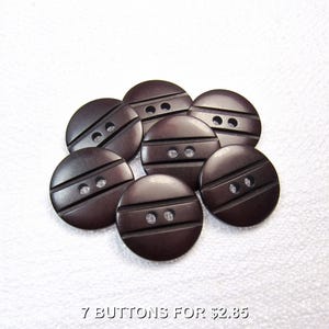 May include: Seven dark brown, round buttons with two horizontal grooves and two holes each. The buttons are arranged in a circular pattern against a white background. The text "7 BUTTONS FOR $2.85" is at the bottom.