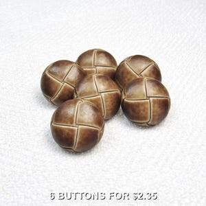 May include: Six brown, round buttons with a geometric design. The buttons are a mix of light and dark brown, with a textured appearance. The buttons are arranged on a white surface.
