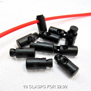 May include: Ten black plastic clasps for cords or straps. The clasps are about 1 inch long and have a small hole on each side. The text "10 CLASPS FOR $2.00" is printed on a white surface below the clasps.