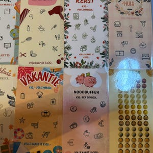 Op de afbeelding: Een verzameling kleurrijke krasloten met verschillende thema's, waaronder school, beauty, Kerstmis, huis en vakantie. Elke kaart bevat thema-illustraties en de tekst "€10,- PER SYMBOOL" en "VOLLE KAART IS €100,-".