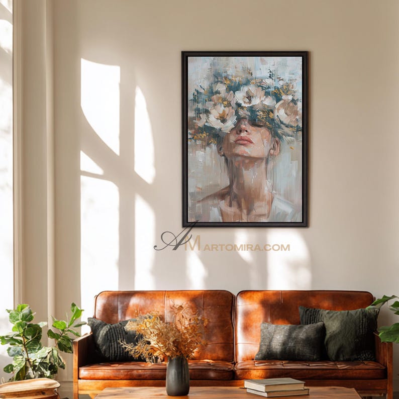 K&ouml;nnte beinhalten: Ein gerahmtes Gem&auml;lde zeigt eine Frau mit einem Blumenkranz. Das Kunstwerk verwendet eine ged&auml;mpfte Farbpalette mit Beige-, Wei&szlig;- und Braunt&ouml;nen. Das Gem&auml;lde wird &uuml;ber einem braunen Ledersofa mit gr&uuml;nen Kissen ausgestellt. Die Website-Adresse ARTOMIRA.COM ist sichtbar.